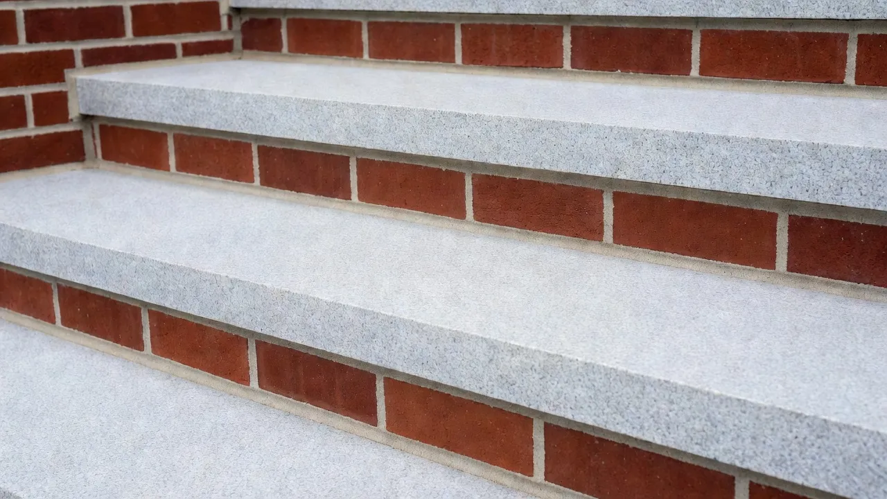 Classic red brick front stoop steps with smooth granite step treads.